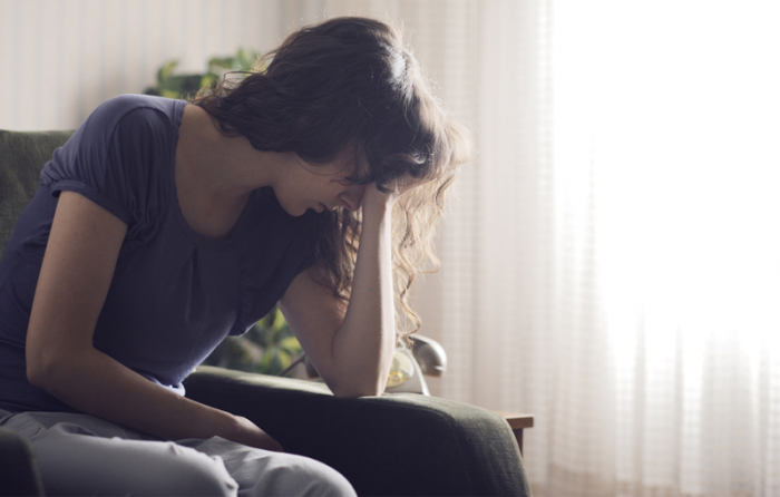 ソファーに座り悩んだ様子の女性