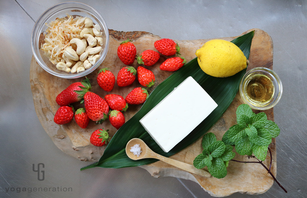 木製カットボードの上のイチゴやレモン、ナッツなどの材料