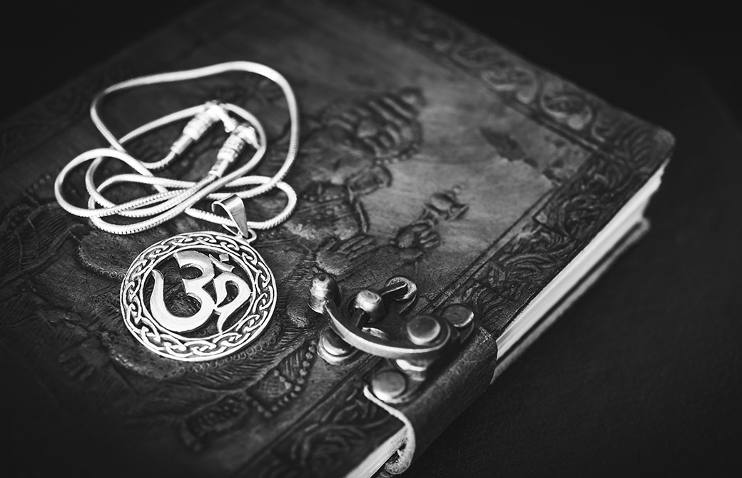 オームのマークのペンダントと古い本