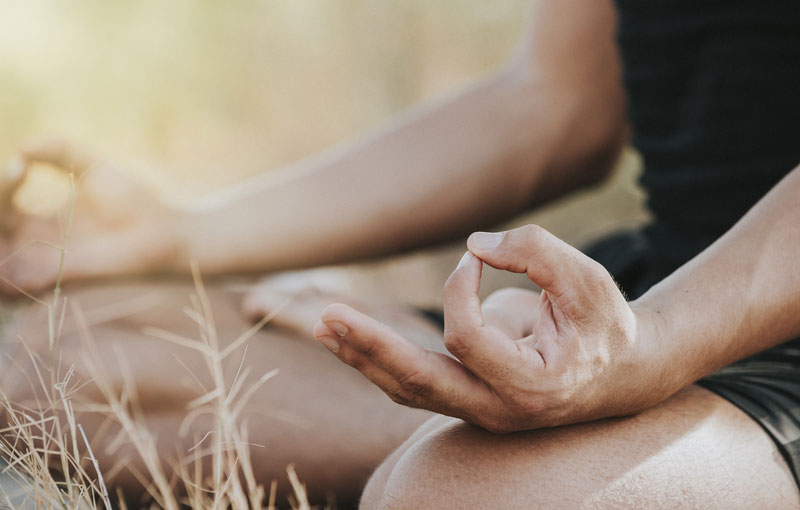 あぐらを組んだ膝の上でチンムードラの指を組んでいる男性