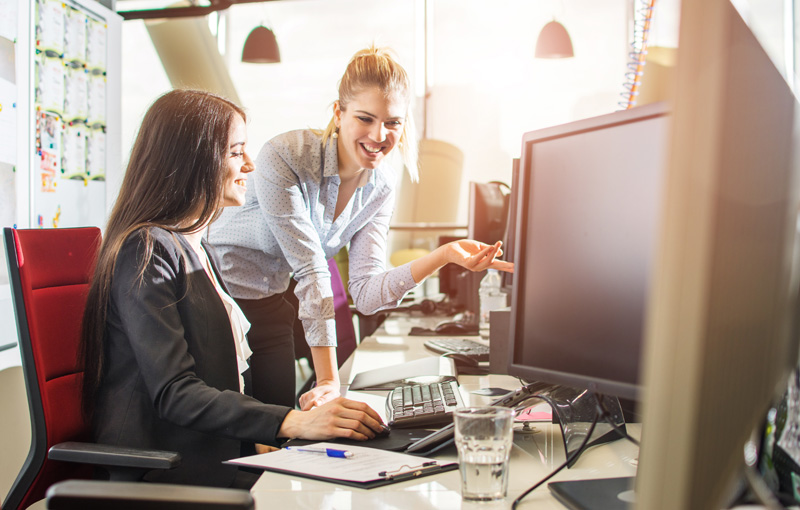 先輩社員が笑顔で後輩に指導している