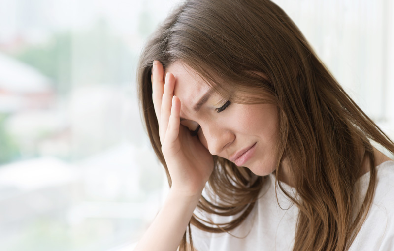 手を額に当て下を向き目を瞑る女性