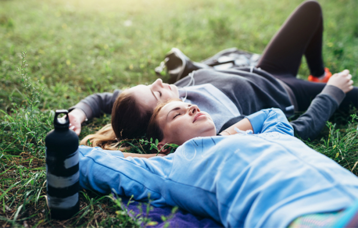 スポーツウェアを着た女性が2人芝生の上で寝転んでいる