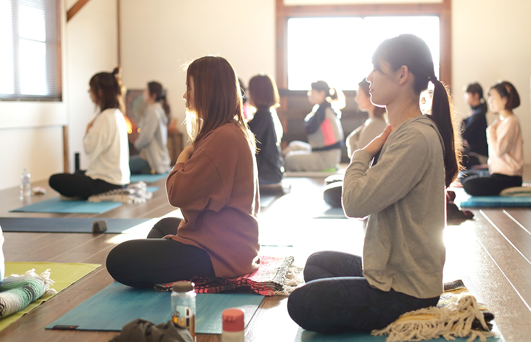 ヨガマットの上で胸に手をあてる生徒さんたちの写真