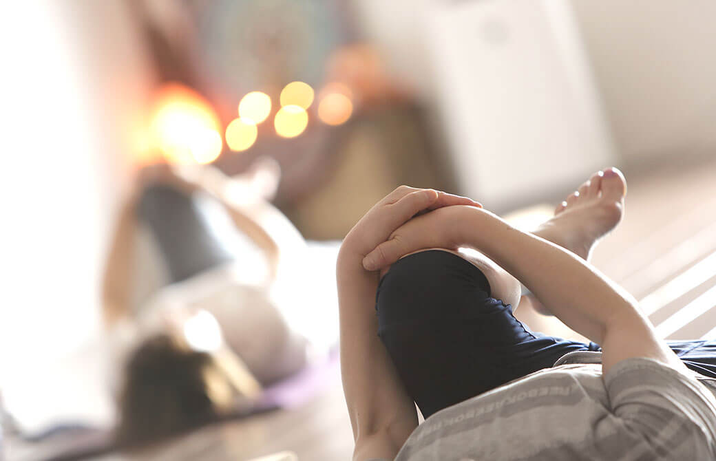 ヨガインストラクター田村佳世さんのヨガクラスで女性が寝転がって膝を抱えている写真