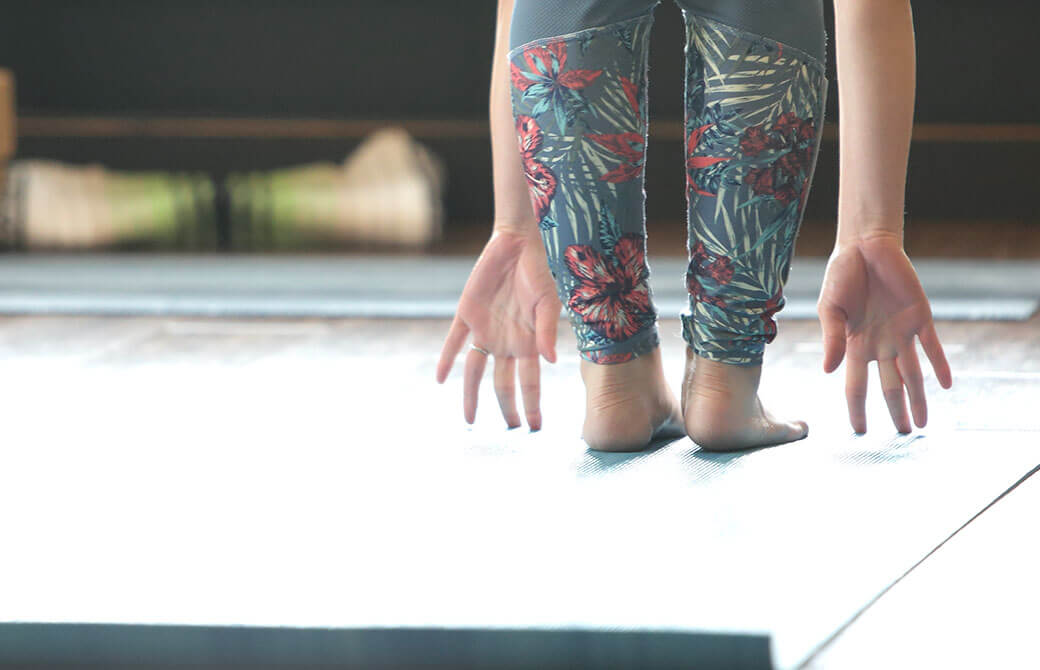 ヨガマットの上で女性が前屈をしている画像