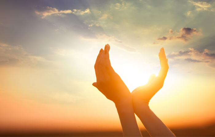 太陽に両手をあてている