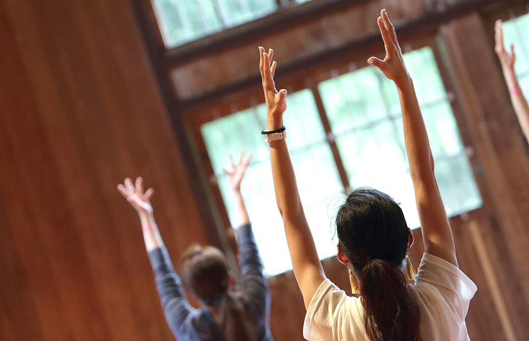 体育館でヨガクラスをしていて、生徒さんが両手を挙げている写真