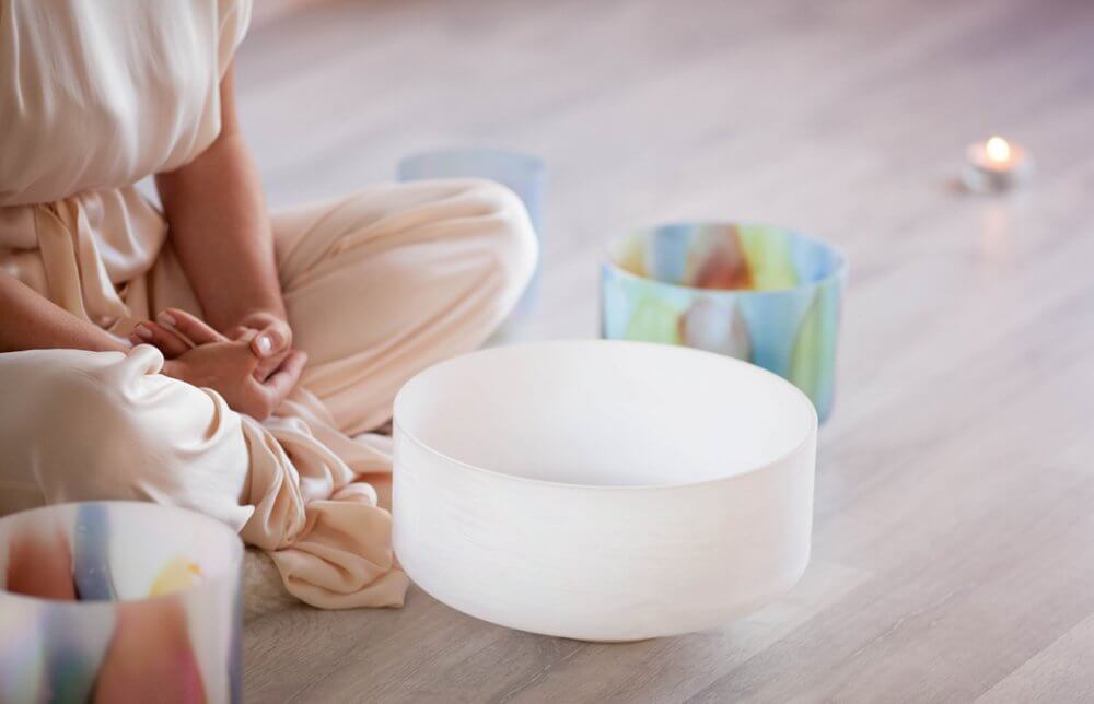 美しいクリスタルボウルが並んでいて女性があぐらを組んでいる