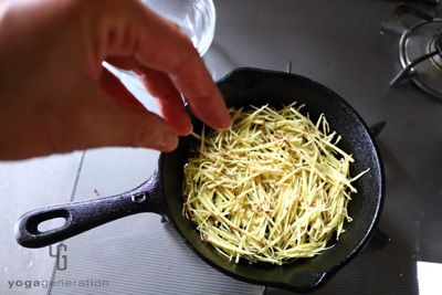 フライパンのサツマイモに水を振り入れる