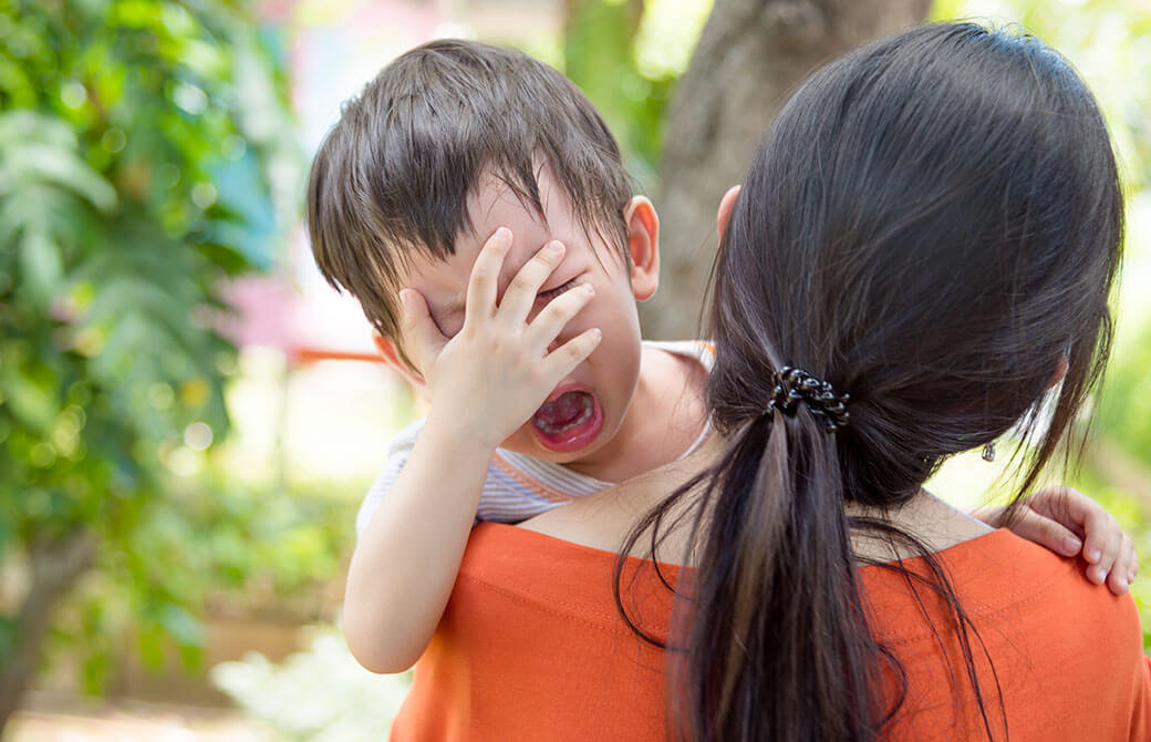 お母さんに抱っこされて泣いている子ども