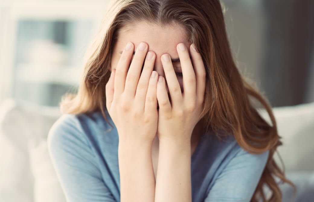 女性が手で顔を覆っている