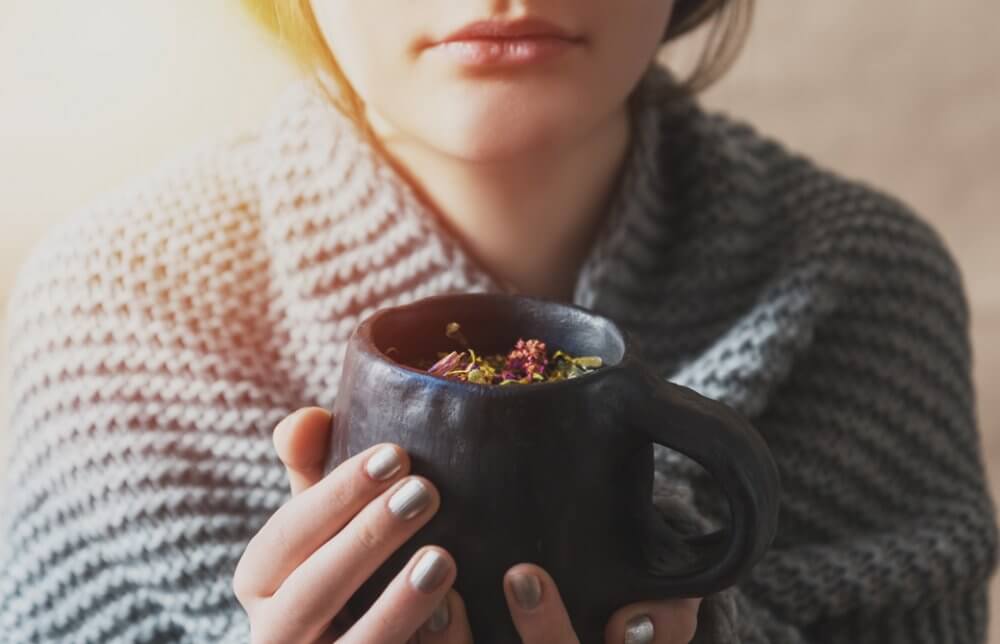 ハーブティーのカップを両手で持った女性