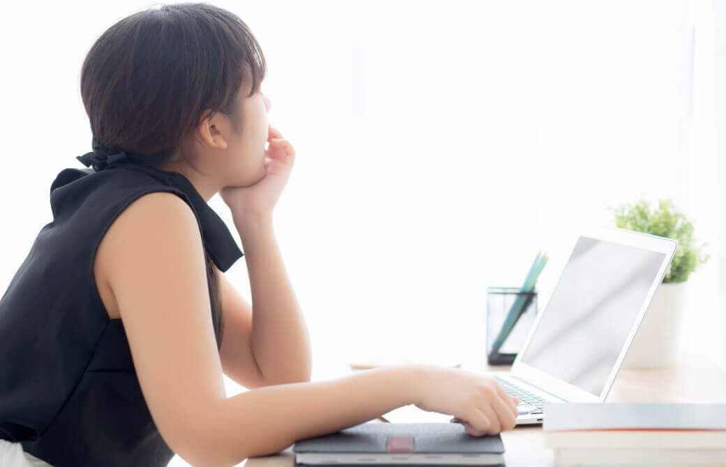 パソコン作業中に物思いにふける女性