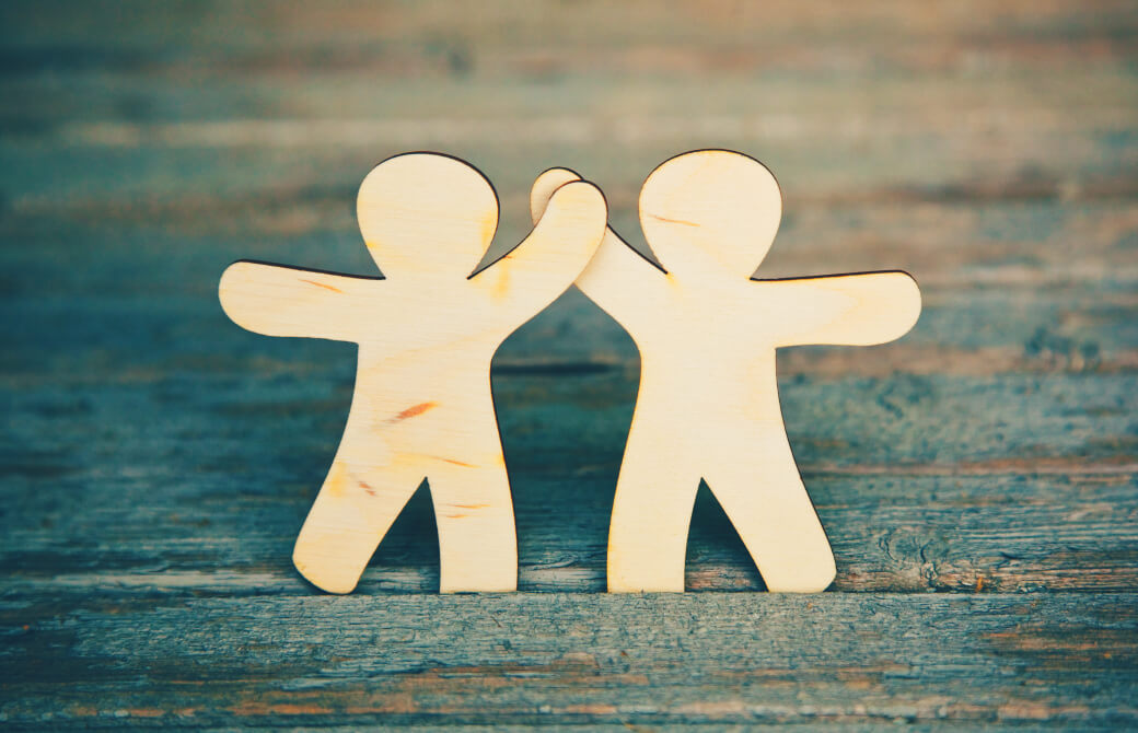 ハイタッチをする木でできた人形たち