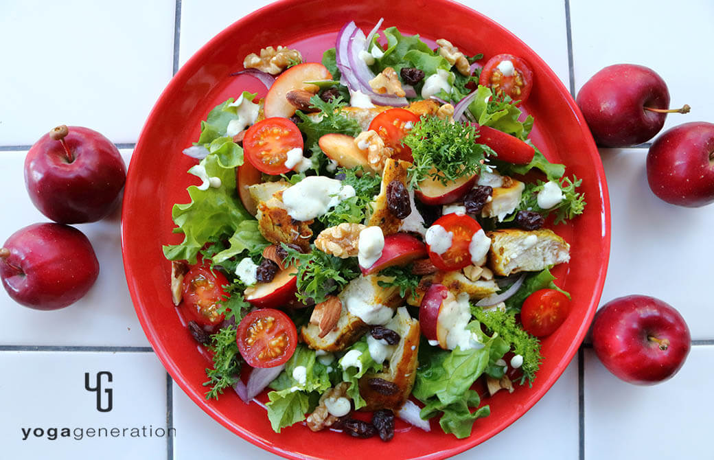 赤いお皿に盛り付けたスパイシーチキンとフレッシュなリンゴのサラダ