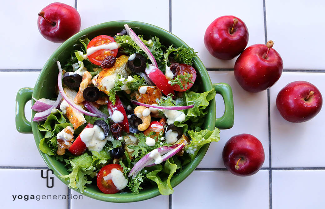 緑のお皿に盛りつけたスパイシーチキンとフレッシュなリンゴのサラダ