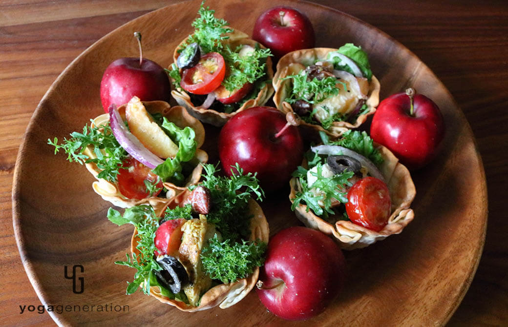 餃子の皮の器に盛りつけたスパイシーチキンとフレッシュなリンゴのサラダ