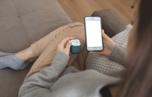 女性がスマートフォンとイヤホンを持って座っている