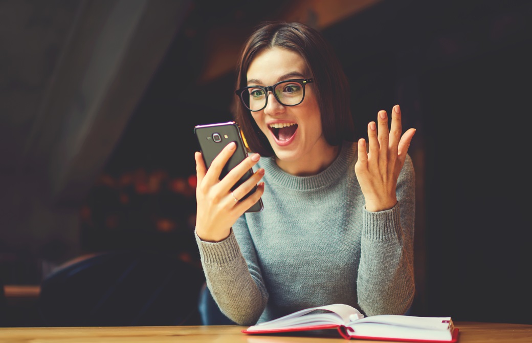 携帯を見て驚いているメガネの女性