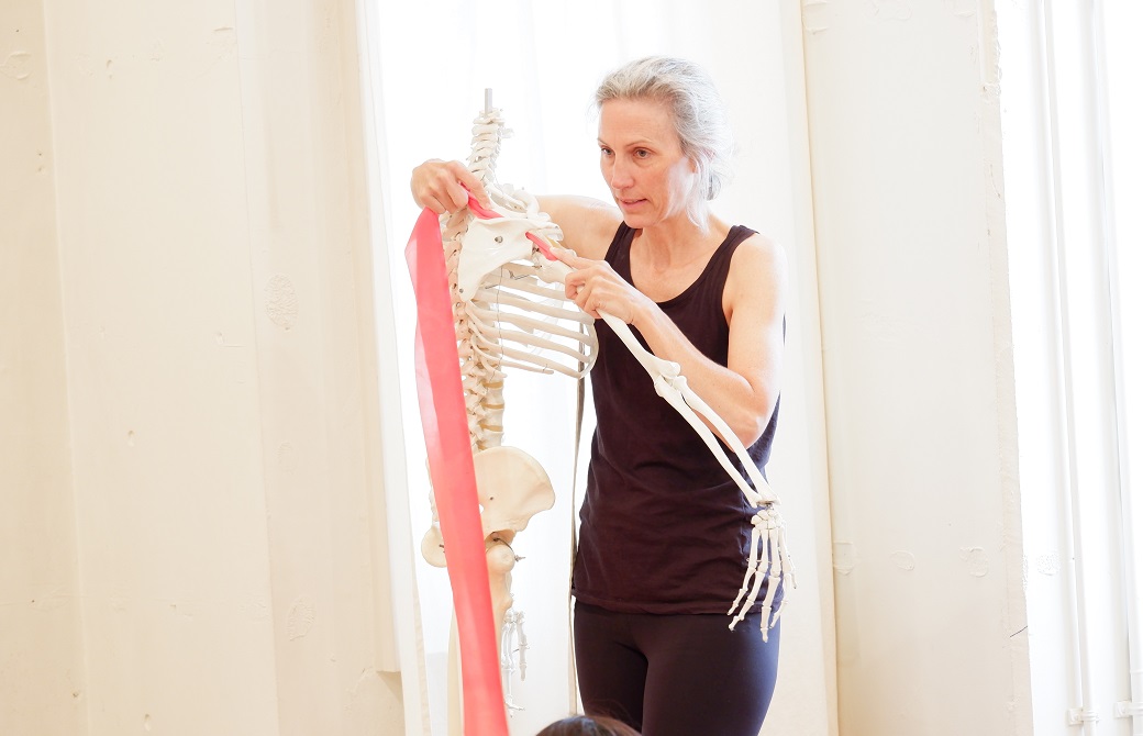 骨とバンドで説明をする、黒のトップスを着たマリア・カ－スティン