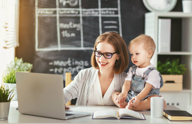リモートワークをする母親と傍に座る子供