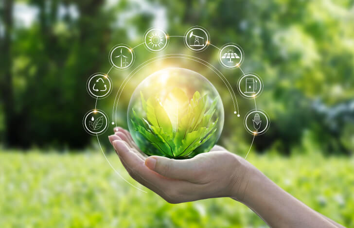 森林の背景の前でサステナブルを象徴するオブジェを持つ人の手