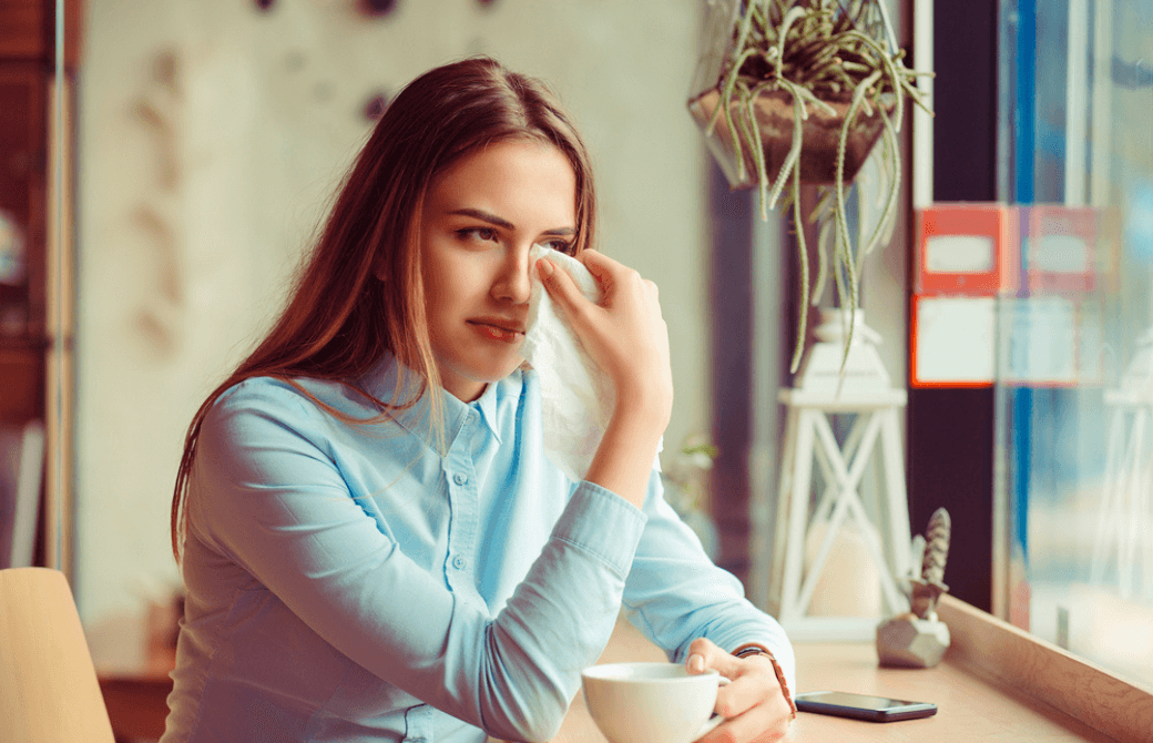 窓際で涙をふく女性