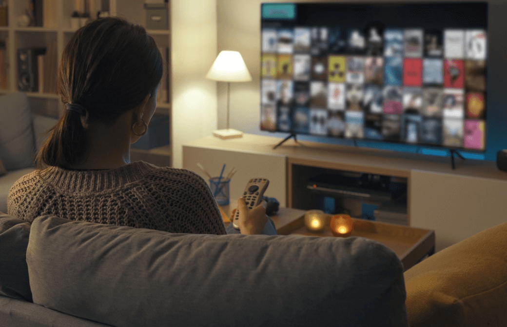夜の部屋でソファに座りテレビ番組を選ぶ女性