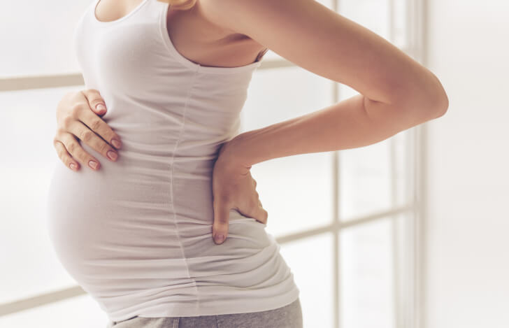 腰痛のために腰に手を当てる妊婦