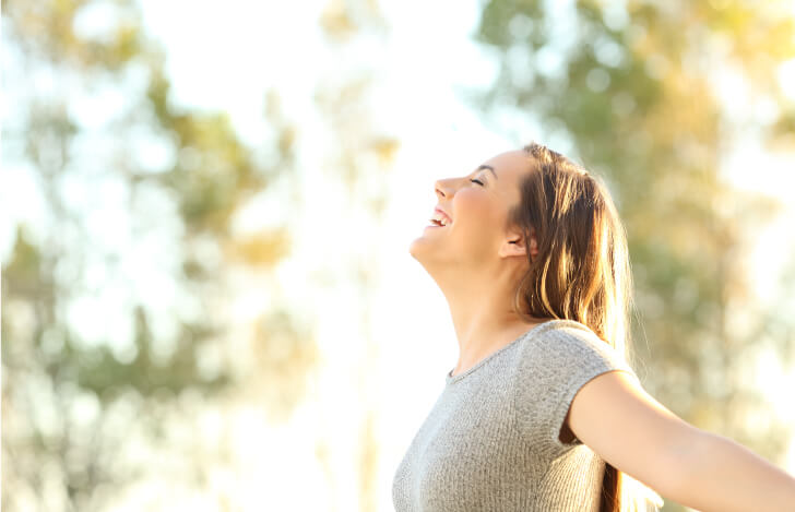 自然の中で深呼吸をする女性