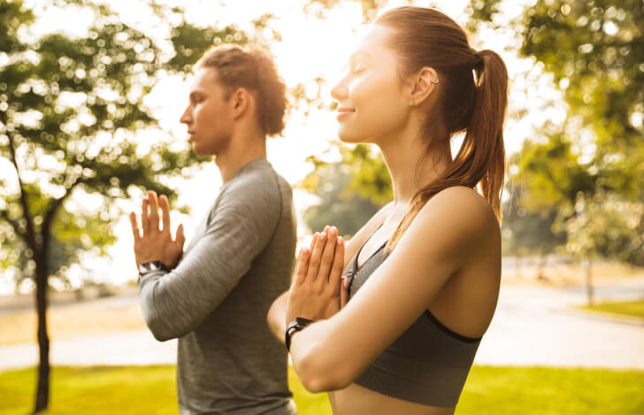 自然の中でヨガをする男女