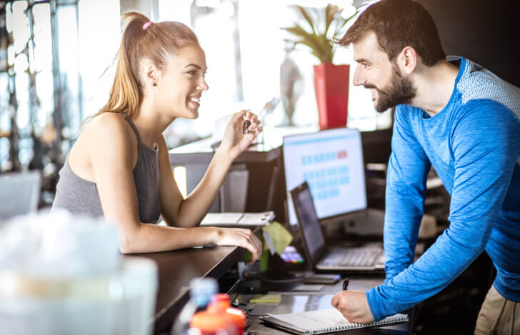 ヨガスタジオの受付で会話する男女