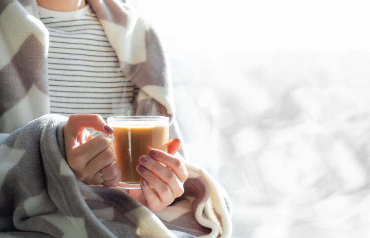 温かい飲み物を手にした女性