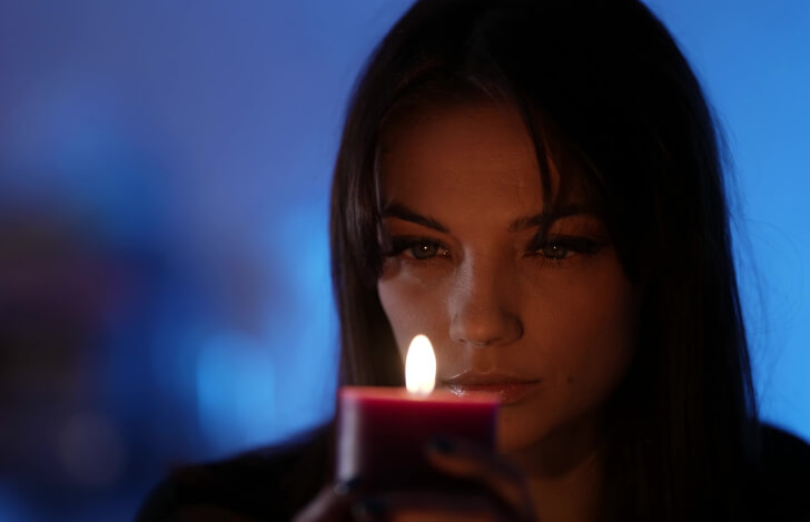 キャンドルの炎を見つめる女性