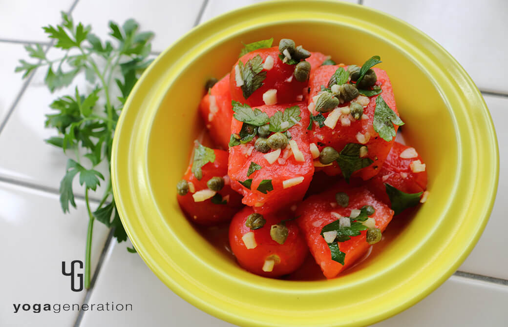 黄色のお皿に盛り付けたスイカとトマトのガーリック・ケイパー・サラダ