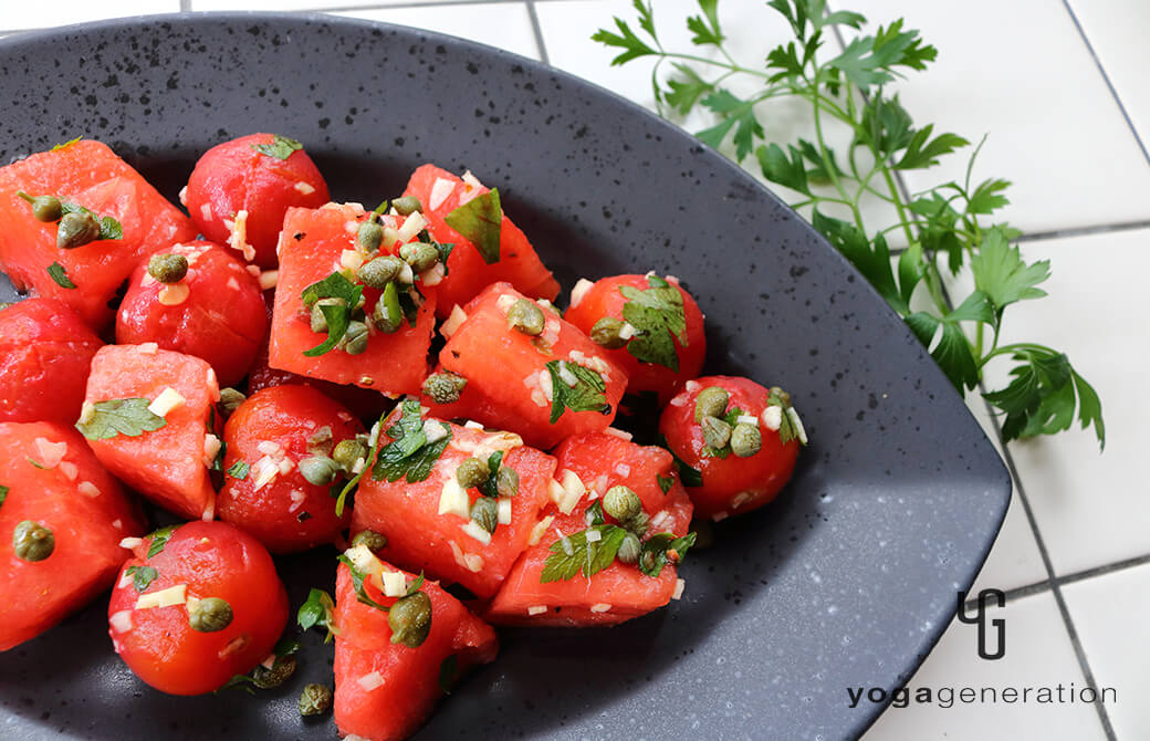 黒いお皿に盛り付けたスイカとトマトのガーリック・ケイパー・サラダ