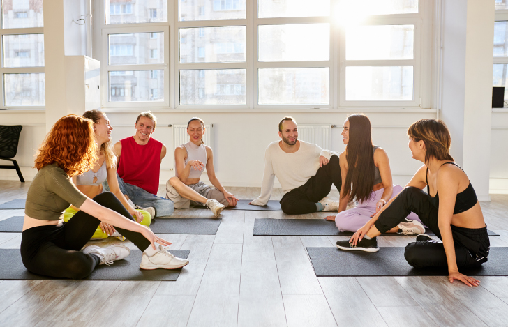 スタジオの中でヨガマットに座り談笑する人々