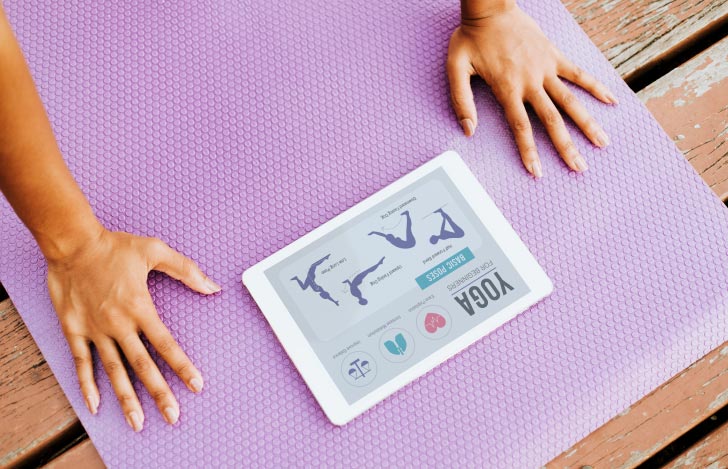 ヨガマットの上でアブレットを置いてヨガをする人の手