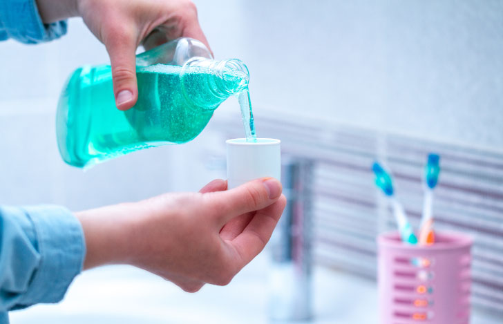 洗面台の前でマウスウォッシュを注ぐ手元