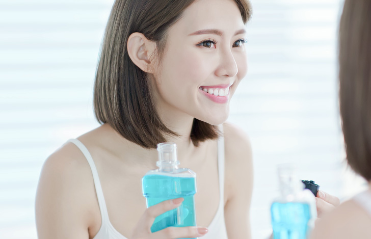 マウスウォッシュでうがいをする女性