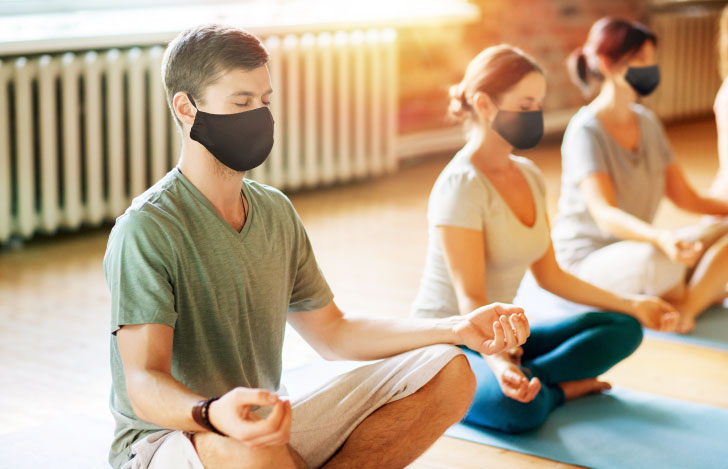マスクをして安楽座で座るヨガの練習生たち