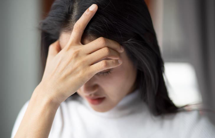 頭痛で頭を抱える女性