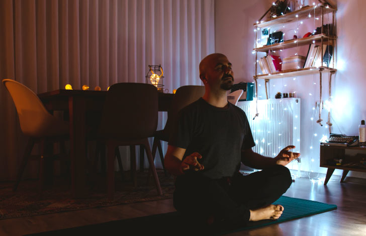 わずかな照明の薄暗い部屋でヨガをする男性