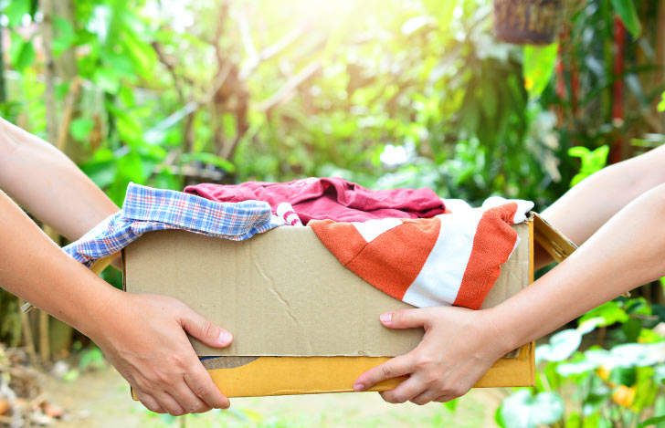 段ボールに入った洋服を手渡しする人の手