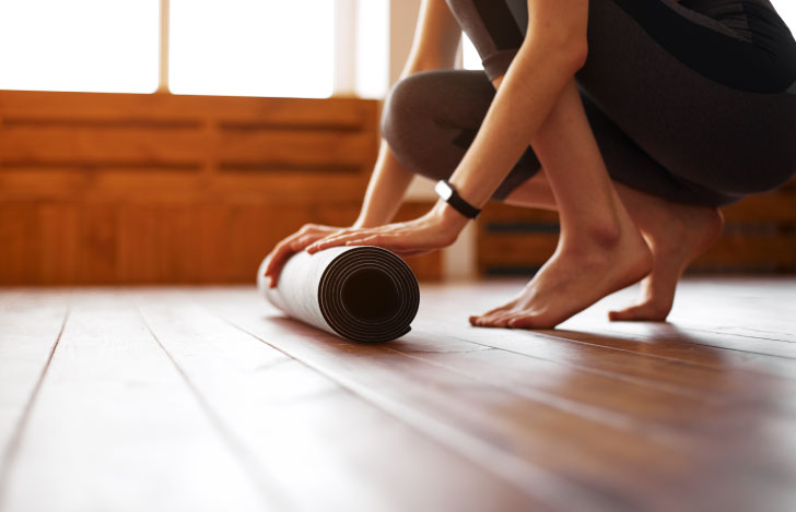 ヨガマットを丸める人の手