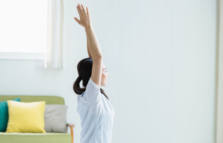 頭上で合掌する女性の横姿