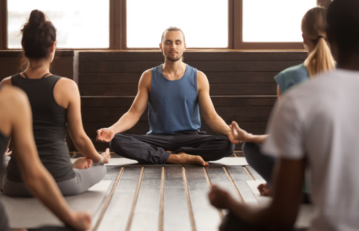 生徒の前に座る男性ヨガ講師と生徒たちの背中