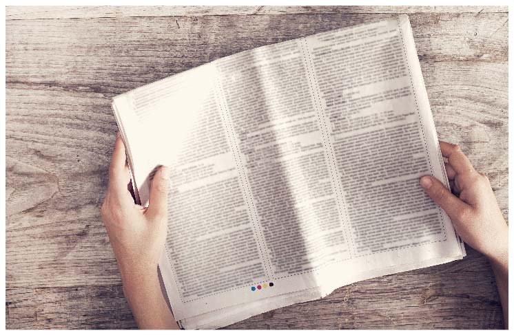 木のテーブルの上の新聞を広げる手