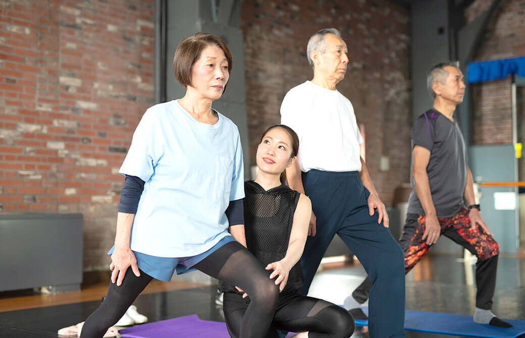 シニア世代にヨガ指導をする女性インストラクター